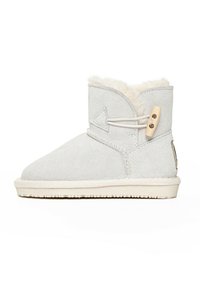 Stivale alla caviglia in suede grigio con punta rotonda, morbida fodera in pelle di pecora, toggle in pelle decorativo e suola in gomma bianca texturizzata.