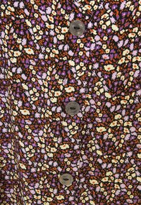 Robe en tissu à fleurs avec un fond noir, comportant de petites fleurs blanches, violettes et orange, et des boutons ronds gris le long de l'avant.