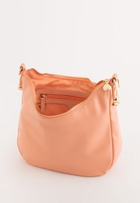 Bolso de mano de piel de melocotón con herrajes dorados, cierre de cremallera y bolsillo interior. Textura suave y lisa, forma redondeada y diseño casual.