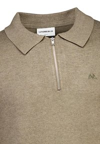 Beige stickad polo med dragkedja i kragen, ribbad krage och en broderad logotyp i det övre vänstra hörnet. Slim fit-design, strukturerad tyg.