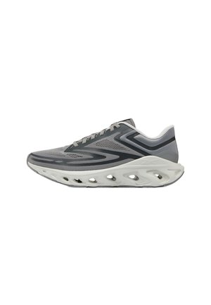 Grijze en zwarte sportschoen met een unieke witte zool met meerdere grote ventilatiegaten en patroonoverlays op het bovenwerk.