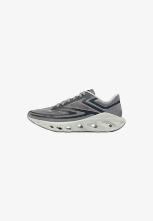 Grauer und schwarzer Sportschuh mit einer einzigartigen weißen Sohle, die mehrere große Belüftungslöcher und gemusterte Überzüge am Obermaterial aufweist.