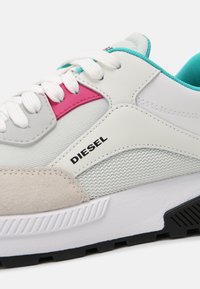 White sneaker with pink and teal accents, featuring a mix of smooth and textured materials, subtle branding, and a chunky sole design.