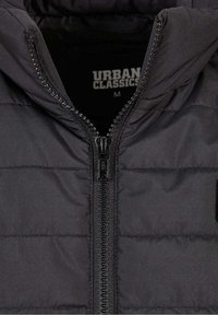 Černá péřová bunda s vysokým límcem, zapínáním na zip a prošívanou texturou. Štítek uvádí "URBAN CLASSICS," velikost M.
