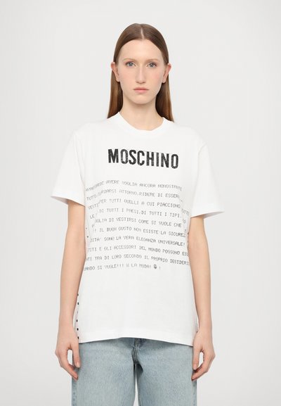 Fehér pamut póló fekete szöveggel és a "MOSCHINO" logóval. Rövid ujjú, laza szabású, oldalsó gomb részletekkel.