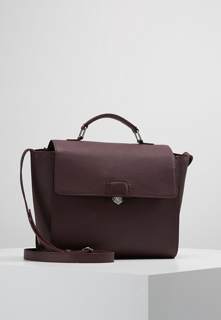 Sac à main en cuir marron foncé avec poignée supérieure et bandoulière ajustable, avec un rabat avant et une fermeture argentée, sur une surface blanche.