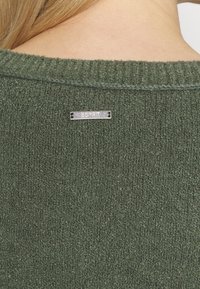 Zielony sweter o fakturowym wzorze z prążkowanym dekoltem oraz metalową metką z napisem "ESPRIT" z tyłu.