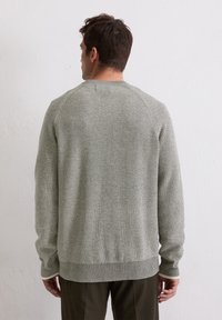 Pull en tricot gris clair avec une texture côtelée, un col rond et des manches longues. Présente un ourlet et des poignets contrastants.