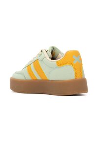 Zapatilla de ante verde con rayas amarillas, cordones beige y suela de goma. Presenta un acento naranja en el talón con un detalle gráfico.