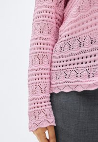 Ροζ ανοιχτόχρωμο πλεκτό πουλόβερ με περίπλοκα μοτίβα ανοιχτής ύφανσης και οδοντωτές άκρες, με μακριά μανίκια και άνετη εφαρμογή.