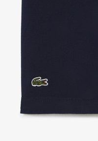 Polo shirt in cotone blu navy con un piccolo logo di coccodrillo ricamato in verde e bianco sul lato sinistro del petto.