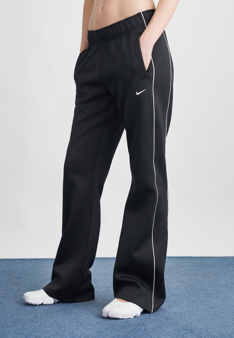 Pantaloni sportivi negri cu croi lejer, talie elastică, buzunare laterale și detalii albe pe cusături. Logo-ul mărcii este vizibil pe șold.