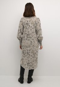 Lång grå klänning med blommig leopardprint, puffärmar och åtsittande manschetter. Bärs med svarta ankelskor. Mjuk tyg och avslappnad form.