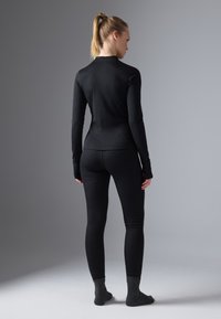 Czarny longsleeve z długim rękawem i pasującymi legginsami wykonanymi z elastycznej, gładkiej tkaniny. Strój charakteryzuje się dopasowanym krojem i rękawami z otworami na kciuki.