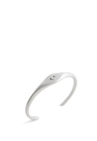 Srebrna bransoletka w kształcie mankietu o gładkim, zakrzywionym wzorze; posiada mały okrągły akcent blisko górnej części oraz fakturowane wykończenie.