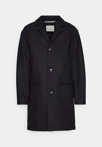 Svart ullrock med utskurna slag, femknappsstängning, två framfickor och en slät yta. Enkelt och klassiskt design.