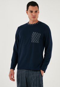 Tamnoplava košulja dugih rukava s teksturiranim kariranim džepom i izrezom. Uparen s odgovarajućim kariranim pidžama hlačama u tamnoplavim nijansama.