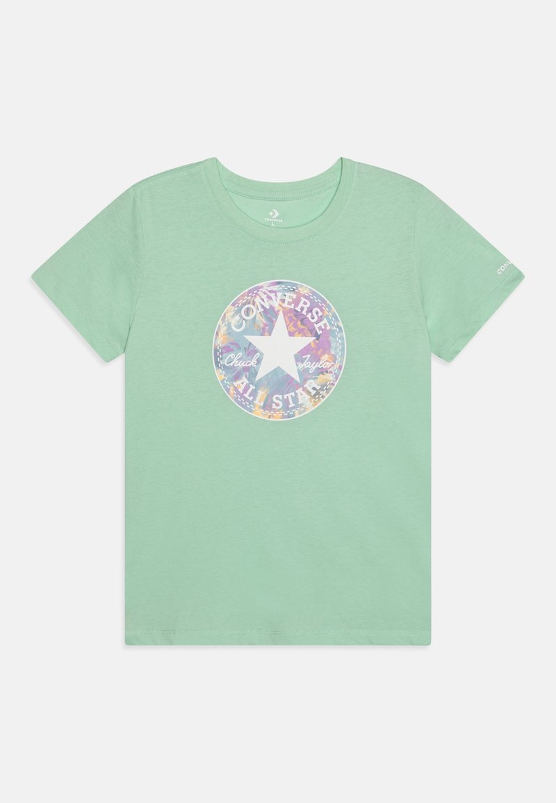 T-shirt vert clair à manches courtes avec un logo rond multicolore Converse All Star et un texte au centre, ainsi qu’un petit texte blanc sur la manche gauche.