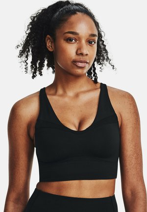 Black sports bra in a fitted design with a v-neck and thick straps. Made from a smooth fabric with subtle textured accents.