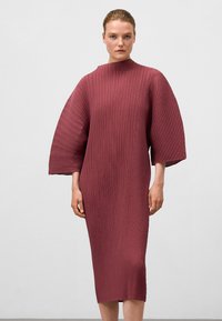 Bordeauxfarbenes plissiertes Kleid mit einem hohen Halsauschnitt und weiten Ärmeln, das eine vertikale Rippstruktur aufweist und bis zur Mitte der Wade reicht.