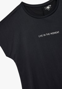 Sort T-shirt lavet af blødt stof, med rund hals og korte ærmer. Forsiden har trykt teksten "LEV I ØJEBLIKKE" i hvid.