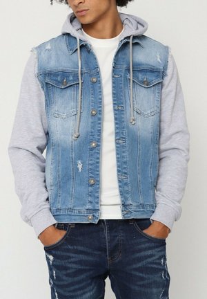 Veste en denim avec une capuche grise attachée ; présente des détails usés, deux poches poitrine et des boutons pression en métal ; délavé bleu.