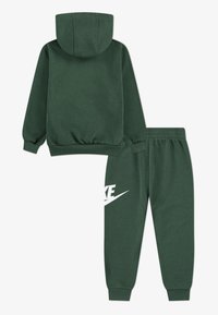 Conjunto de sudadera y pantalones de chándal en verde oscuro, con un bolsillo tipo canguro, puños acanalados y un logo de Nike blanco en la pierna izquierda. Material de forro suave.