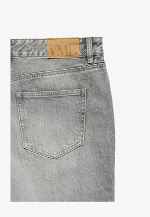 Hallide hallide teksad, millel on ristkülikukujuline tagatasku ja tan värvi nahkpatch, millel on vöökoha peal reljeefne "VMD" brändimine.