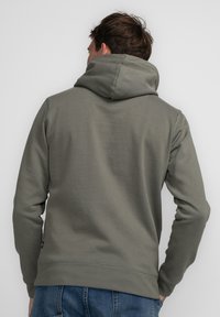 Sudadera gris hecha de un tejido suave, con una gran capucha, mangas largas y un diseño limpio y sencillo con un dobladillo acanalado.