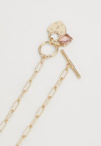 Χρυσό κολιέ με κλειδαριά σε σχήμα καρδιάς, ροζ κρύσταλλο και αλυσίδα με σχέδιο συνδεδεμένων κρίκων και κλείσιμο τύπου toggle.