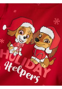 Roter Pullover mit zwei Cartoon-Hunden in Weihnachtsmützen, schneebedeckten Akzenten und dem Text "HOLIDAY Helpers" in Weiß und Pink.