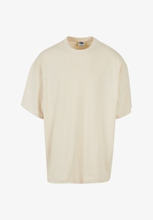 Kremowa koszulka z krótkim rękawem o luźnym kroju i okrągłym dekoltem; wykonana z miękkiej bawełny, z subtelnymi detalami przeszyć.