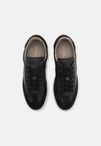 Sneakers neri con una combinazione di pelle liscia e camoscio. Design classico con lacci, interno beige e branding discreto.