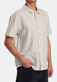 Short-sleeve button-up shirt in light cream with vertical red stripes. Features a collar and a chest pocket, made from a textured fabric.