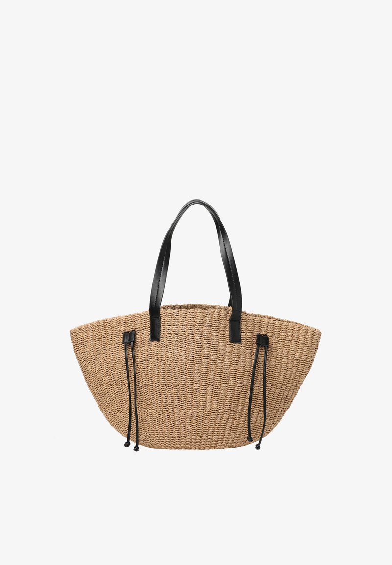 Sac fourre-tout en paille tissée avec des poignées en cuir noir et des cordons en cuir noir réglables sur les côtés.