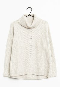 Pull à col roulé en tricot côtelé beige avec des manches longues, suspendu sur un cintre noir devant un fond blanc.