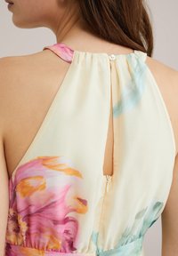 Kukkakuosisella mekolla, joka on valmistettu pehmeästä ja kevyestä kankaasta ja jossa on pastellivärit, avainaukko takana sekä piilotettu vetoketjukiinnitys.