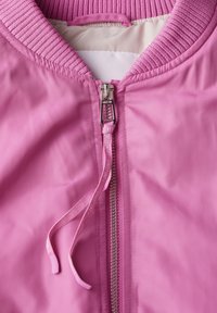 Różowa bomberka z ribbowanym kołnierzem, zamek błyskawiczny i akcenty ze sznurkiem. Gładka tekstura materiału z błyszczącym wykończeniem i metką z logo.