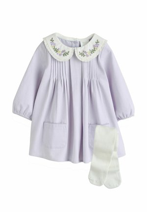 Fliederfarbenes Baby-Mädchenkleid mit langen Ärmeln, weißem Peter-Pan-Kragen, der mit lila Blumen bestickt ist, aufgesetzten Taschen vorne, kombiniert mit weißen Strumpfhosen.