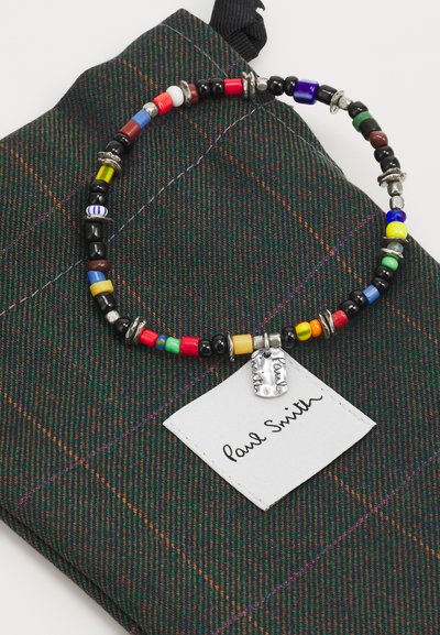 Beaded necklace featuring multicolored round beads and metallic accents. Includes a silver tag with “Paul Smith” on a textured dark plaid pouch.