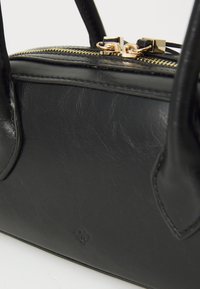 Schwarze Lederhandtasche mit Reißverschluss und goldenen Beschlägen. Hat eine glatte Textur und ein kleines Logodetail an der Seite. Doppelte Tragegriffe.