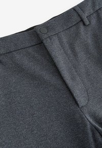 Graue gewobene Anzughosen aus strukturiertem Stoff, mit einem verdeckten Reißverschluss, schwarzem Knopfverschluss und Gürtelschlaufen an der Taille.