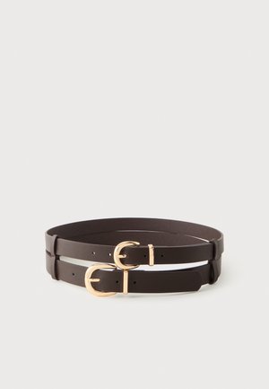 Deux ceintures en cuir marron avec des boucles métalliques dorées, enroulées sur un fond gris clair.