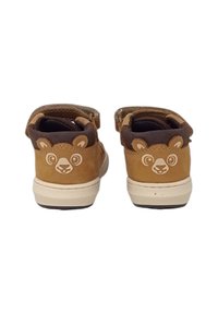 Scarpe per bambini in suede marrone con accenti beige a forma di faccia d'orso sul tallone, dotate di una chiusura in Velcro e con un rivestimento interno texturizzato.