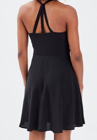 Black sleeveless dress with a fitted bodice and flared skirt. Features a halter neck design with lace accents and a smooth texture.