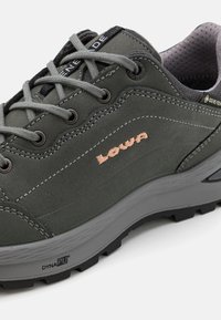 Scarpa da trekking Lowa di colore grigio scuro con lacci grigi chiari. Presenta il marchio GORE-TEX, una tomaia testurizzata e una suola pronunciata per una maggiore trazione.