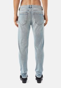 Light blue denim jeans with a straight cut, featuring two back pockets and a faded texture. Worn with black shoes.