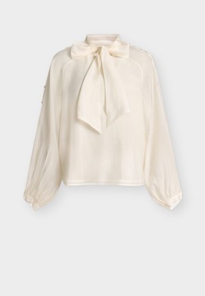 Krémová blúzka s dlhými rukávmi, širokou mašľou na zaväzovanie okolo krku a manžetami zapínanými na gombíky, zobrazená na jednoduchom svetlom pozadí.