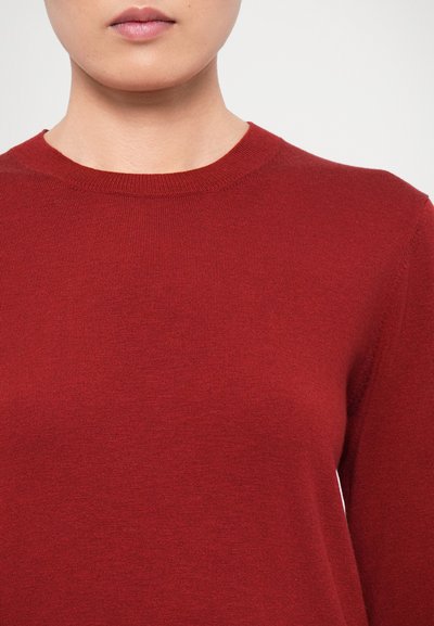 Red, ribbed knit sweater with a crew neckline, featuring a smooth texture and fitted design, showcasing a solid color without patterns.