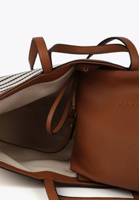 Brun läderaxelväska med texturerad yta, med ett randigt tygfoder och en liten matchande innerväska. Handtagen är robusta.